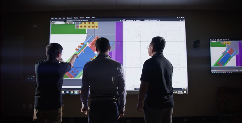 Engineers looking at modeling software on a projected screen.