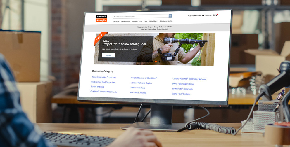 Man sitting at desk viewing computer screen. Computer screen is showing the Customer Portal login page.