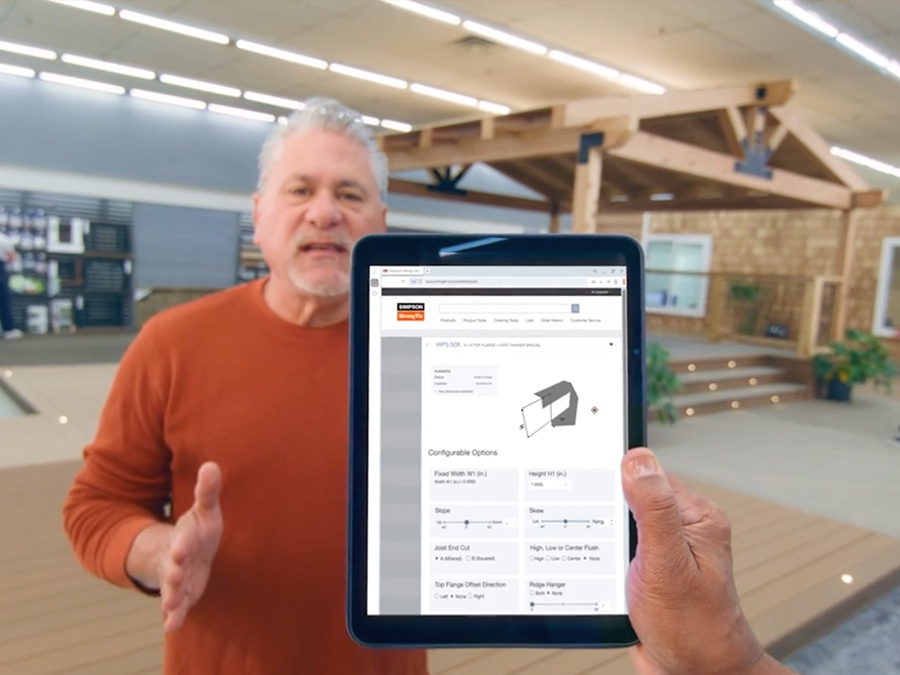 Hand holding tablet with a screenshot of a Customer Portal page in front of a man wearing an orange sweater inside of a store.