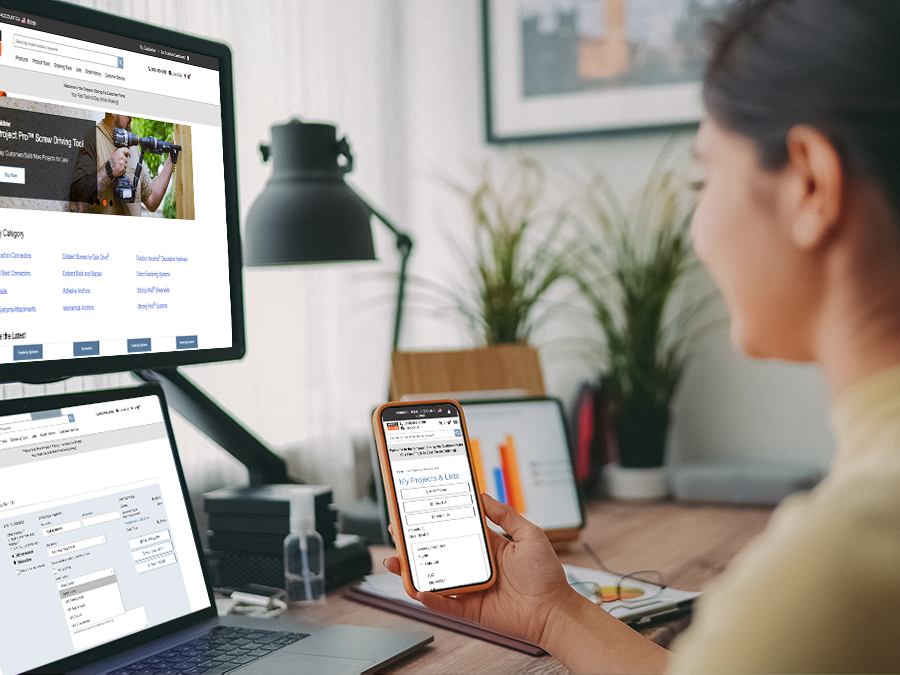 Woman looking at multiple devices displaying the Strong-Tie Simpson home page, and customer portal pages on a monitor, laptop, and mobile device in a home office setting.