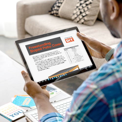 A person holding a tablet displaying DIY instructions for a "Freestanding Sloped Patio Cover" from Simpson Strong-Tie, with detailed plans and a project diagram.