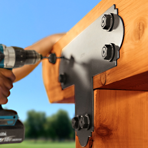 A person uses a power drill to install Simpson Strong-Tie outdoor accents on a sturdy wooden beam for structural support.