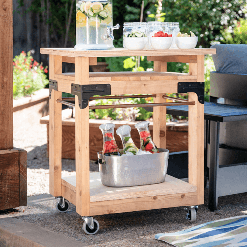 Homemade wood and connector mobile cart with water pitcher filled with lemons and limes.