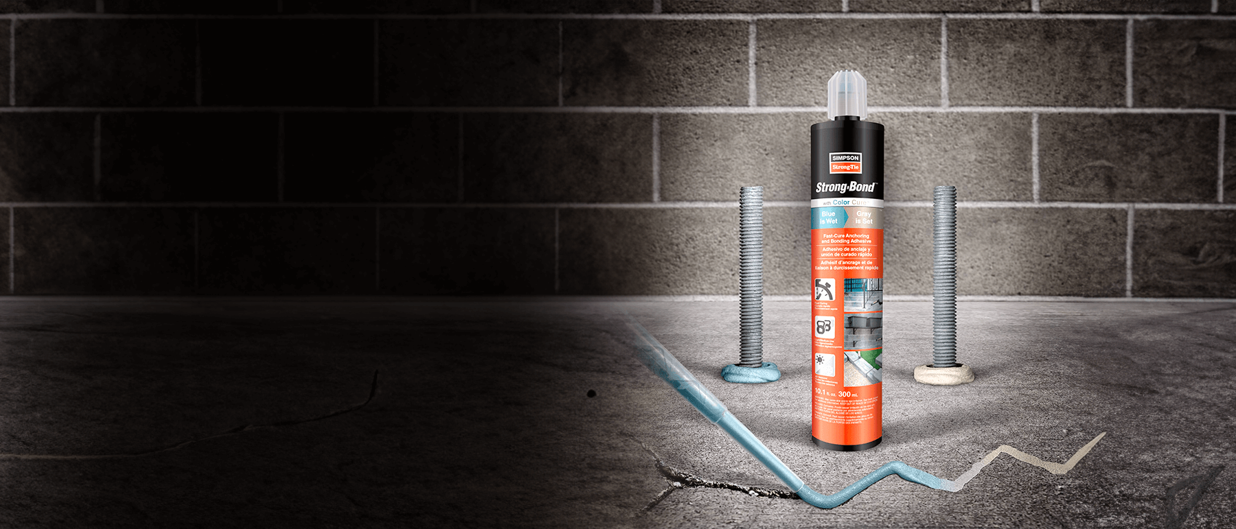 Strong-Bond adhesive tube on cracked concrete with bolts and blue adhesive line; brick wall in background.