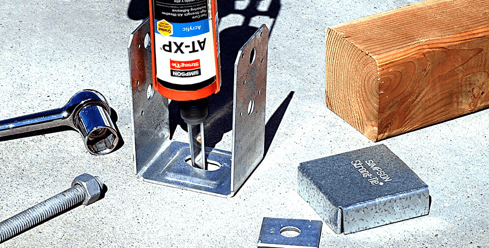 Simpson Strong-Tie AT-XP adhesive anchor system being applied to a metal base bracket, with accompanying bolt, wrench, and wooden beam.