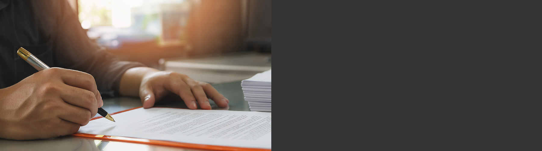 Man's hand holding a metal pen signing a contract.