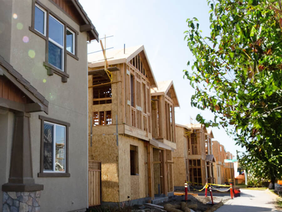 Concrete finished house followed by a row of unfinished houses under construction.