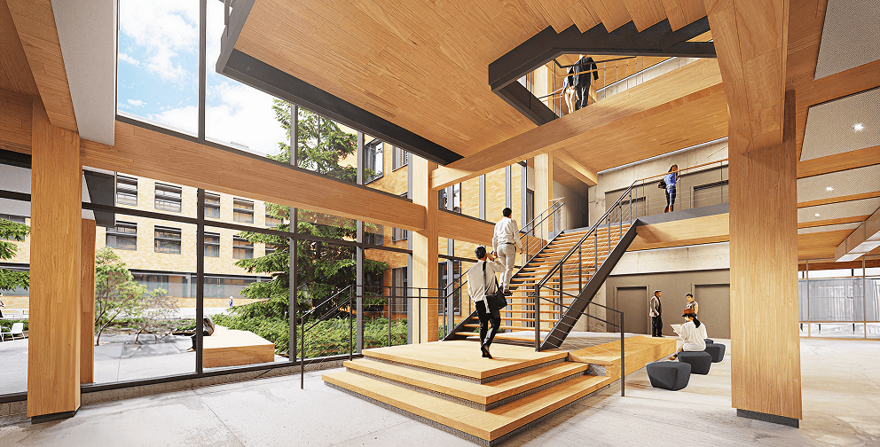 Interior view of a modern mass timber building featuring exposed wood beams, a central staircase, large windows, and people walking through the open space.