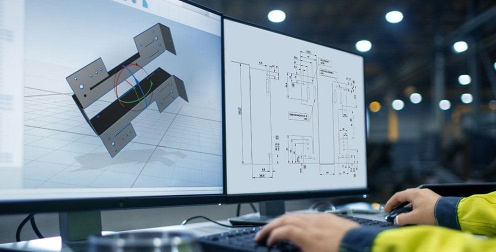 Man typing on keyboard at a desk with two large monitors, one screen displaying a 3d render of a product and other screen is displaying a drawing.