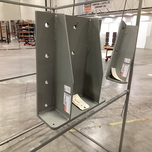 Custom-fabricated steel components hanging on rack in a warehouse.