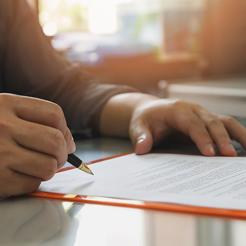 Man signing contract on desktop.