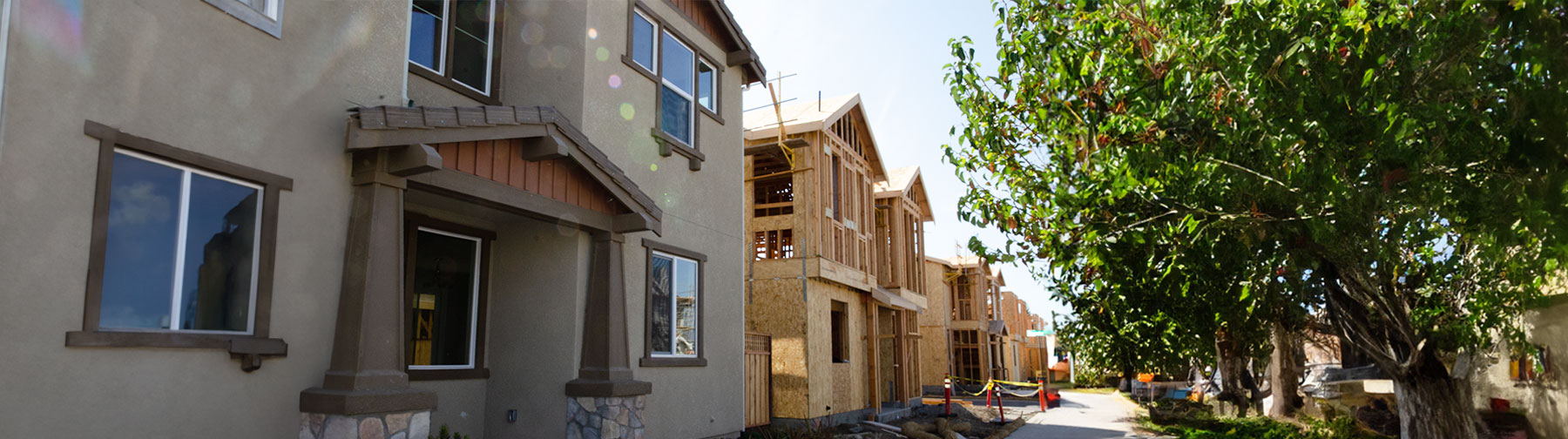 Concrete finished house followed by a row of unfinished houses under construction.