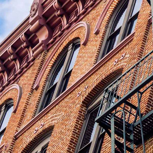 Side of red bricked building, windows and fire escape