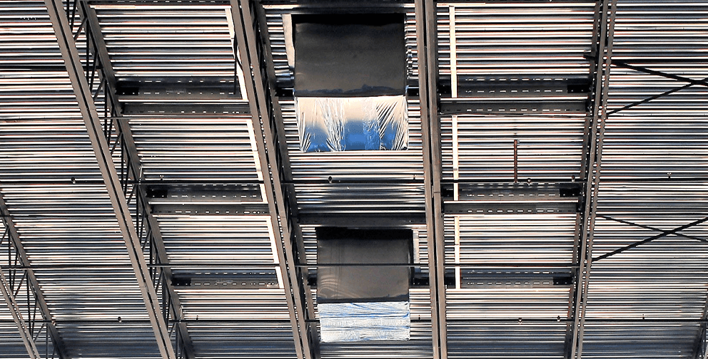 A ceiling structure with metal decking and steel framing, showing framed openings for future installations such as HVAC or skylights.