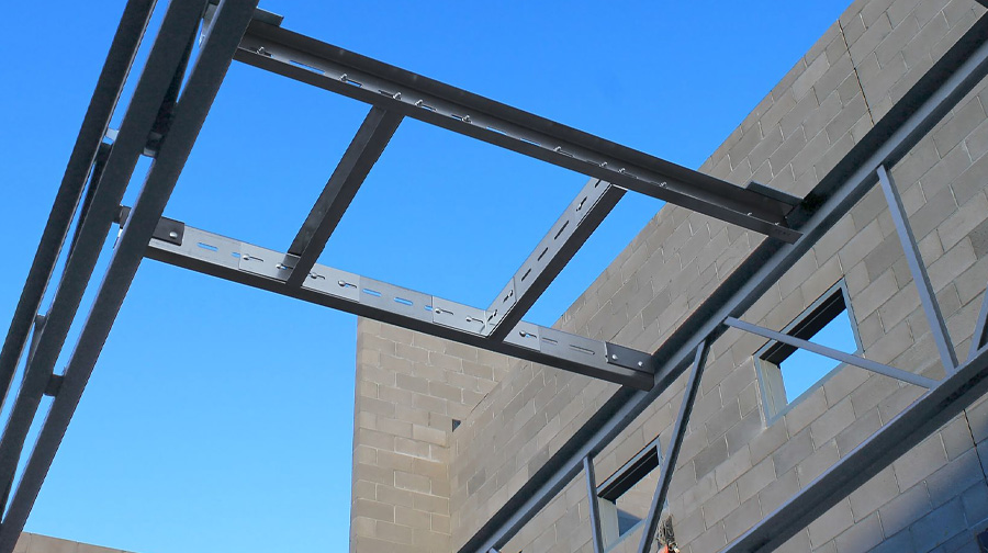 The QuickFrames™ is shown installed between concrete masonry walls, enabling fast, bolt-together structural steel framing for commercial construction.